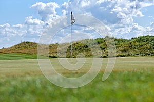 Background of green golf field with flagstick marking hole