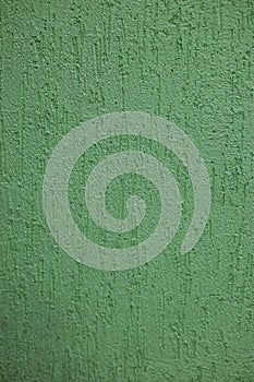 Background of a green painted textured wall inside a house. Wallpaper for painting green color with uneven surface. The