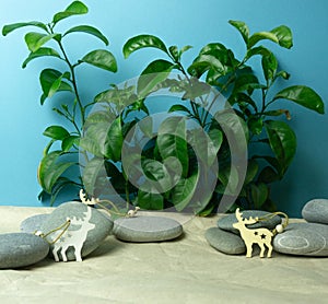 Background from green plants, sea pebbles, wooden craft paper deer.