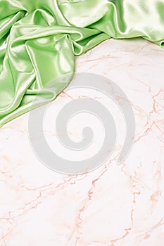 Background with green silk fabric on light marble