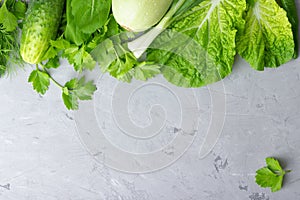 Background with green vegetables, salad, cucumber,green onion and zucchini on gray stone table top