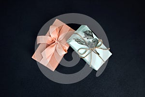 Background for greetings. Gifts wrapping in soft pink paper with dry eucalyptus branch on a black concrete background