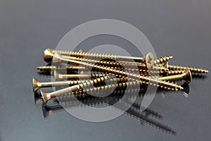 Iron long screws lie in one pile on a black background
