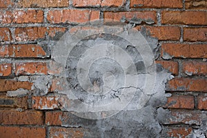 Background of grunge red brick wall with concrete patch  . close up view