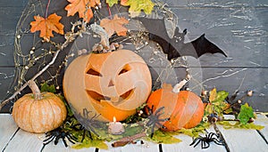Background with halloween pumpkins, candles and autumn leaves on the wooden house porch