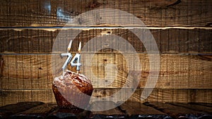 Background happy birthday pie or muffin with candles burning digit number 74. Festive card Happy Birthday on the background of