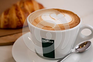 Background image of cappuccino in lavazza cup with croissant