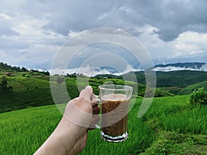 Background image of mountain terraced rice fields holding a cup of coffee in a refreshing morning atmosphere.