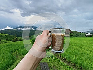 Background image of mountain terraced rice fields holding a cup of coffee in a refreshing morning atmosphere.