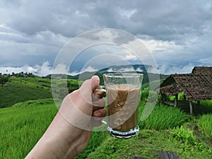 Background image of mountain terraced rice fields holding a cup of coffee in a refreshing morning atmosphere.