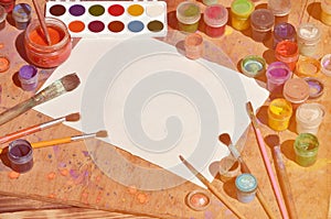 Background image showing interest in watercolor painting and art. A blank sheet of paper, surrounded by brushes, cans with waterc