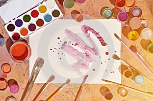 Background image showing interest in watercolor painting and art. A painted sheet of paper, surrounded by brushes, jars of waterc