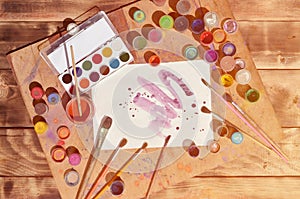 Background image showing interest in watercolor painting and art. A painted sheet of paper, surrounded by brushes, jars of waterc