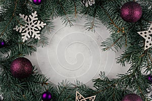 Background image of white surface with branches of Christmas tree, decorations and purple balls. Top view. Copy space