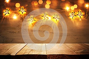 Background image of wooden board table in front of Christmas warm gold garland lights. filtered. selective focus. glitter overlay