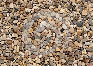 Background of large amount of little dark, brown, red and yellow stones view from above