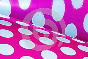 A background of large white dots on pink paper.