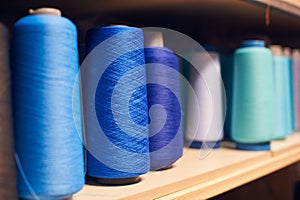 Background with a lot of blue coils with threads. Bobbins are stacked in a rows, one on the other. Selective focus