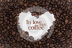 Background made of coffee beans in a heart shape with message `In love with coffee`