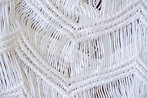 Background made with white knitted fabric threads making a nice and cozy texture. Abstract white image resembling a fabric.