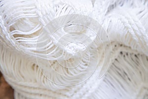 Background made with white knitted fabric threads making a nice and cozy texture. Abstract white image resembling a fabric.