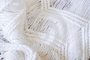 Background made with white knitted fabric threads making a nice and cozy texture. Abstract white image resembling a fabric.