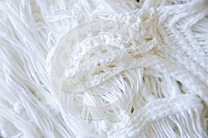 Background made with white knitted fabric threads making a nice and cozy texture. Abstract white image resembling a fabric.