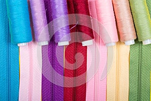 Background made of zippers and coils with threads of different colors.