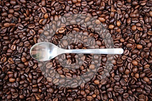 Background with many coffee beans and metal spoon photo