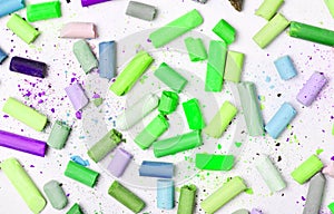 Background of many multicolored pastel crayons on a white background, top view.