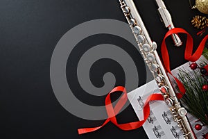 Background with metal flute on black table and Christmas decoration