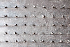 Background of metal surface from sheets with rivets, close-up. Texture of the iron gate. A metal relief backing for