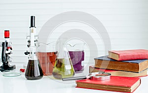 Background of microscopes, books, test experimental tube and magnifying glasses on white table for studying science in class.