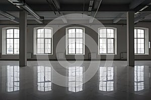 Empty large room in old factory building with row of big windows, columns and pipes under the beton ceiling photo