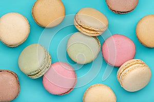 Background from multi-colored macaroons on bright blue background, top view.
