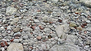 Background with multi-colored stones under clear water