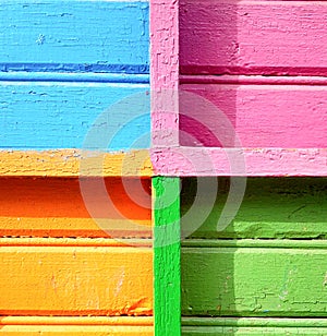 The background of a multi-colored wall made of boards. Texture of the wall painted in blue, pink, yellow and green colors