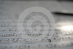 Background of musical notes: score for piano, close-up. Sheet with music notes and pencil