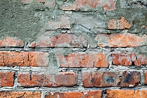 Old orange brick wall with cement patch and cracks