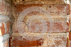 background of an old red brick wall. An unusual design made of bricks and cement of an old building. Cobwebs on the surface of an