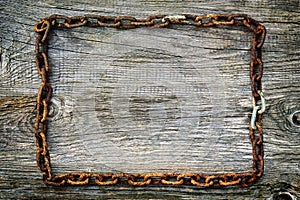 Rusty chain lying on the rough wooden surface in the shape of a rectangle