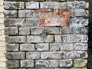 Background of old vintage dirty brick wall with peeling plaster, texture. Old multi colored brick wall. brick with a metal plaque