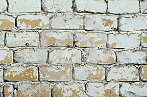 Background of old vintage dirty brick wall with peeling plaster, texture. Peeling paint on beige bricks. close up