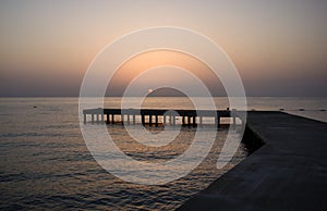 Background with old wooden pier in the sea at sunset