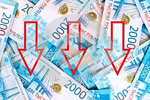 Background of paper russian money, banknotes of 2000 two thousands rubles with red down arrows as a symbol of devaluation russian