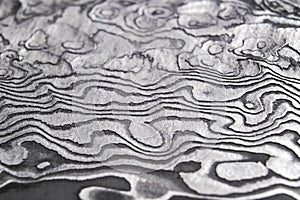 Background with pattern of damask steel. Close up. Macro shot of a damascus knife blade texture. Damascus steel pattern. Metal and
