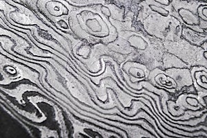 Background with pattern of damask steel. Close up. Macro shot of a damascus knife blade texture. Damascus steel pattern. Metal and