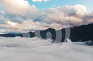 Background photo of low clouds in a mountain valley, vibrant blue and orange sky. Sunrise or sunset view of mountains