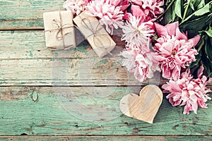 Background with pink peonies, gift box and a wooden heart on old