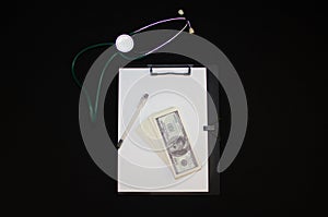 Background with place to insert. On a black background lies a stethoscope and a medical tablet with a stack of one